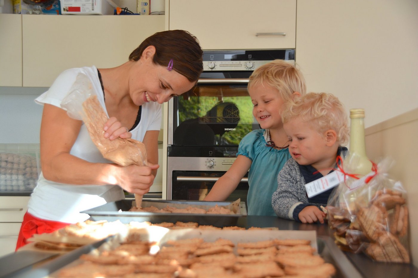 Maya Herger füllt ihre "Herzli-Guetzli" mit Praliné-Crème. Larissa (4, Mitte) und Selina (2) wissen, dass sie nicht naschen dürfen, "weil Mami damit ein Batzeli dazu verdient." (Bild Andrea Gysin)