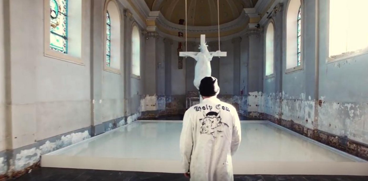 Künstler Tom Herck vor seiner Installation namens «Holy Cow» (Heilige Kuh). Zum Kunstwerk gehört auch ein grosses Becken voll mit Milch. (Bild Screenshot Youtube)