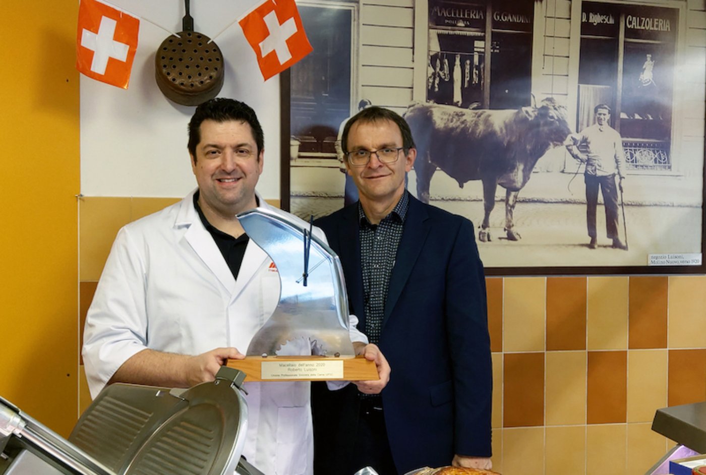 Roberto Luisoni präsentiert mit Stolz seinen Pokal, einer aus einem Blitzmesser gefertigten Uhr. Übergeben wurde ihm die Auzeichnung von Ruedi Hadorn, Direktor des Schweizer Fleisch-Fachverbands. (Hinweis: Die Masken wurden unter Einhaltung des Schutzkonzepts nur kurzzeitig für die Aufnahme abgenommen.) (Bild SFF)
