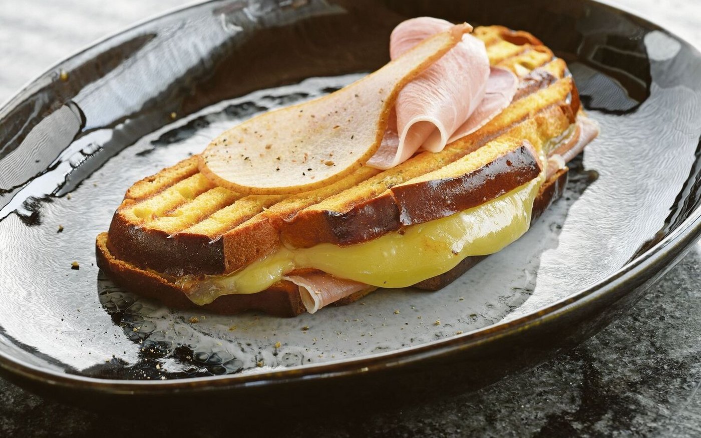 Dieser Croque trägt ganz die Handschrift des Kantons Freiburg. Die Cuchaule, das Freiburger Safranbrot, ist mit Vacherin Fribourgeois und Bénichonsenf gefüllt.   