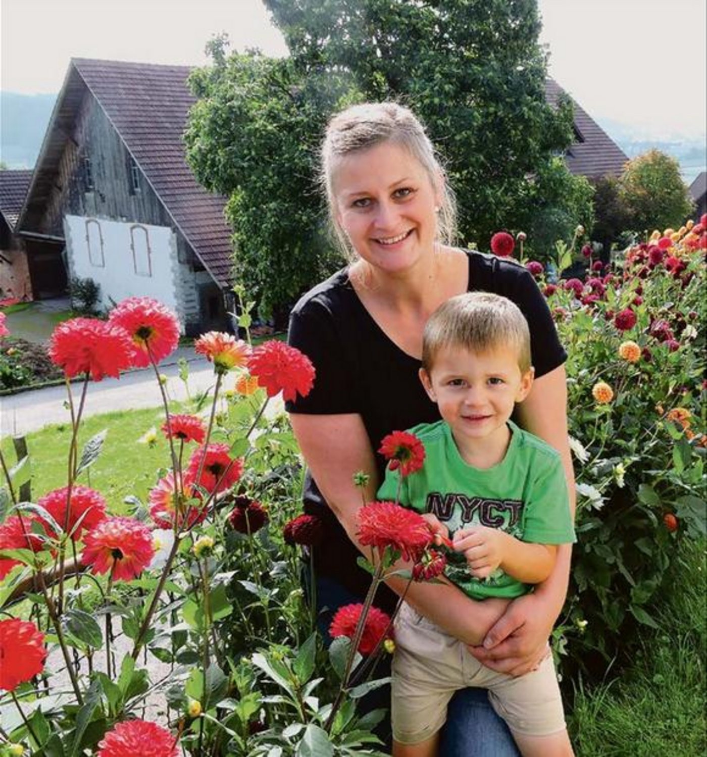 Christa Strub mit Sohn Phil bei ihren Dahlien vor dem Haus. Sie bewirtet gerne Gäste als Swiss-Tavolata-Gastgeberin. (Bild Barbara Heiniger)